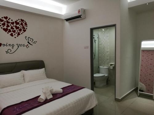 ein Schlafzimmer mit einem Bett mit einem Herz an der Wand in der Unterkunft D' Cozy Inn in Malakka