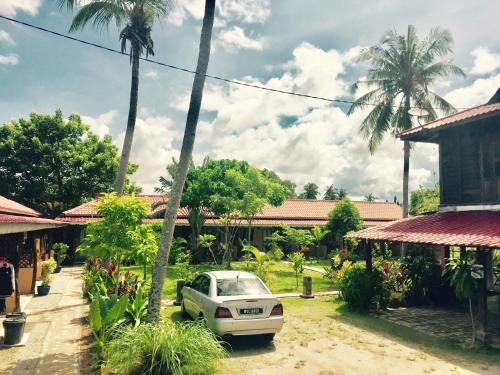 a car parked in front of a house with palm trees at Soluna Guest House in Pantai Cenang