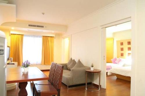a living room with a couch and a bed and a table at The Palazzo Hotel in Bangkok