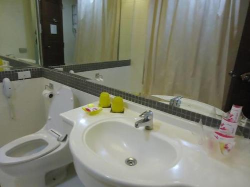 a bathroom with a sink and a toilet and a mirror at The Palazzo Hotel in Bangkok