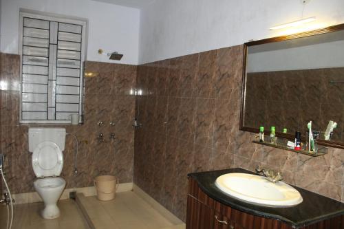 a bathroom with a sink and a toilet and a mirror at Chowdhury's Guest House in Kolkata