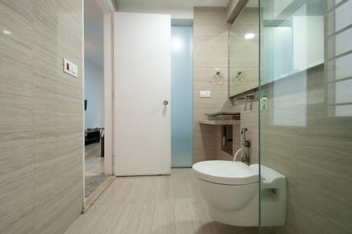 a bathroom with a toilet and a glass shower at Isec Apartment in Mumbai
