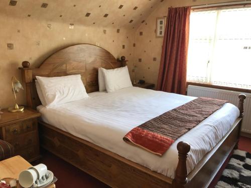 a bedroom with a large bed with a wooden headboard at Wimberley House in Inverness