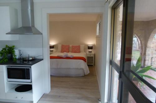 1 dormitorio con 1 cama con almohadas de color naranja y microondas en The Sanctuary at Paradise Beach B&B en Sanctuary Point