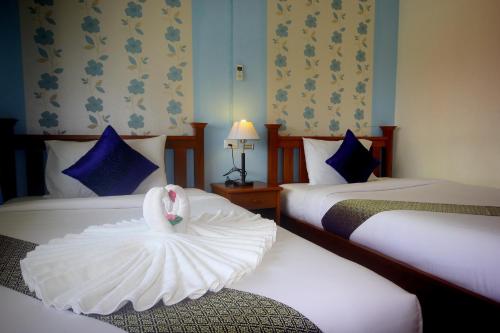 Una habitación de hotel con dos camas con un cisne. en Myplace@Surat Hotel en Surat Thani