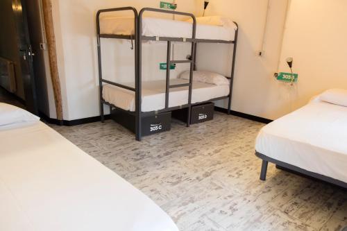 a room with two beds and two bunk beds at Green River Hostel in Cuenca