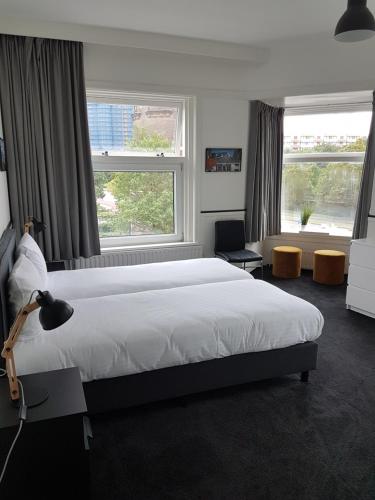 a bedroom with a large bed and two windows at Stad & Strandhotel Elisabeth in Vlissingen