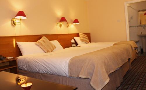 a hotel room with two beds and a desk with a laptop at The Parkway Hotel in Dunmanway