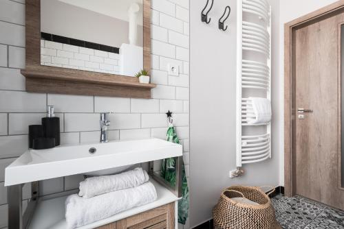 łazienka z umywalką i białymi płytkami metra w obiekcie Csapô Apartment w Debreczynie