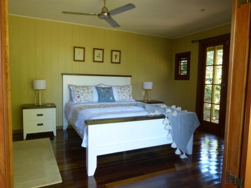 1 dormitorio con 1 cama blanca y 2 mesitas de noche en Magnolia Cottage, en Cooroy