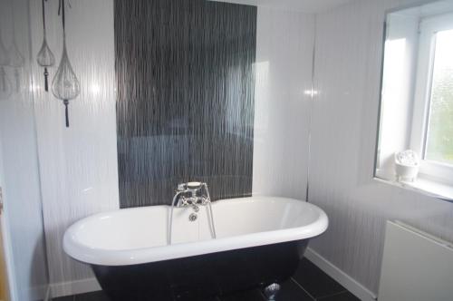 a white bathroom with a tub and a window at Gumtree Cottage in Port Askaig