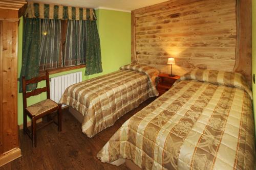 a bedroom with two beds and a wooden wall at Assietta in Sauze dʼOulx