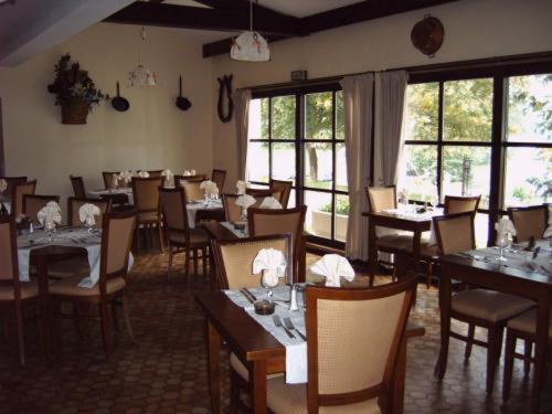 een eetkamer met tafels, stoelen en ramen bij Hotel Restaurant des Lacs in Contrexéville