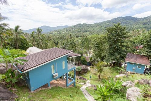 a blue house with mountains in the background at Kiri Tawan in Baan Tai