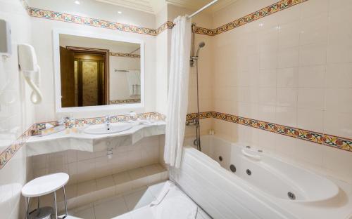 ein weißes Badezimmer mit einer Badewanne, einem Waschbecken und einer Badewanne in der Unterkunft El Mouradi Tozeur in Tozeur