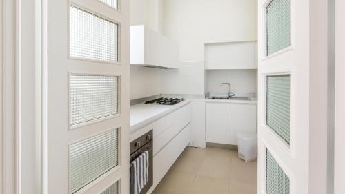 a white kitchen with white cabinets and windows at Scicli Albergo Diffuso in Scicli