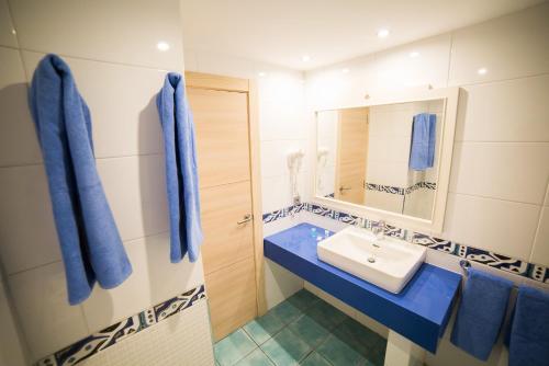 a bathroom with a sink and a mirror and blue towels at Cala D Or Apartamentos in Puerto Rico de Gran Canaria