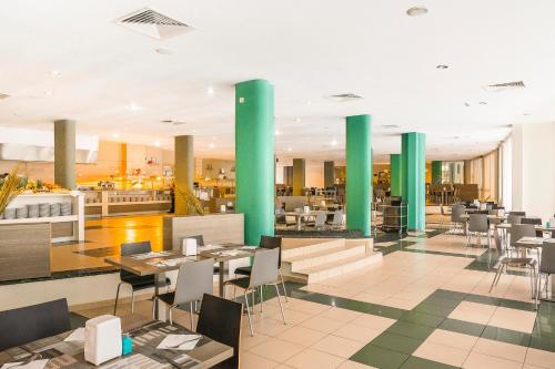 een restaurant met groene zuilen en tafels en stoelen bij MPM Hotel Kalina Garden - All Inclusive in Sunny Beach