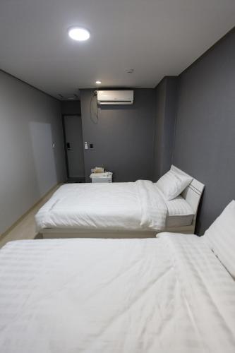two beds in a room with white sheets at O'guest in Haeundae in Busan