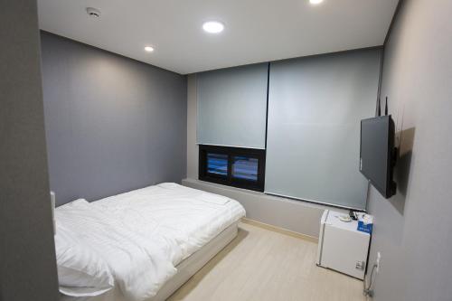um pequeno quarto com uma cama e uma televisão em O'guest in Haeundae em Busan