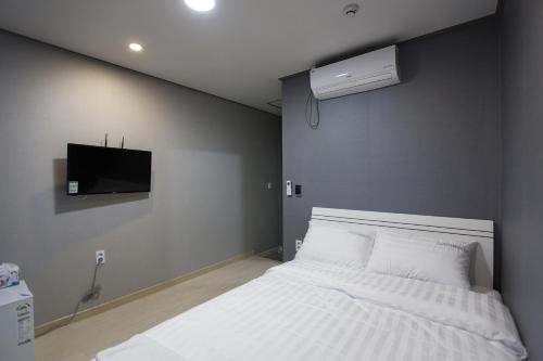 a bedroom with a white bed and a tv at O'guest in Haeundae in Busan