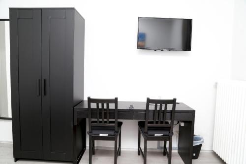 a black dining room table with two chairs and a tv at Main Hotel Frankfurt City in Frankfurt/Main