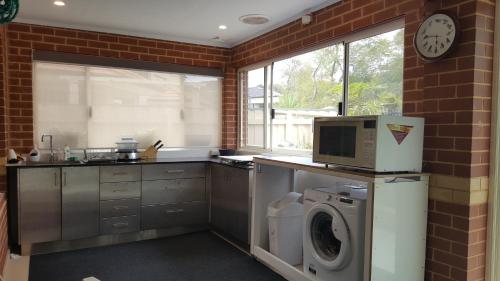a kitchen with a washing machine and a microwave at Vimal's Homestay in Perth