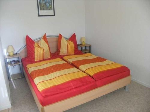 DwasiedenにあるGemuetliche Fewo Sonnenuntergang Wのベッドルーム1室(大型ベッド1台、赤と黄色の枕付)