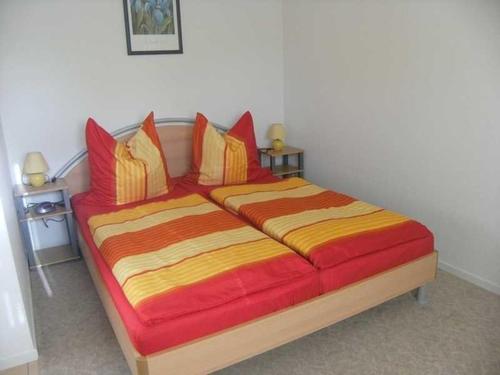 a bedroom with a large bed with red and yellow pillows at Gemütliche Fewo Sonnenuntergang WE52433 in Dwasieden