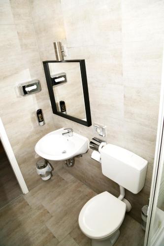 a bathroom with a toilet and a sink and a mirror at Main Hotel Frankfurt City in Frankfurt/Main