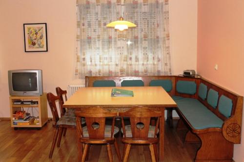 a dining room with a table and chairs and a tv at Ferienhof Weingut Lunzer in Gols
