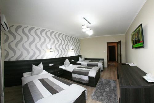 a hotel room with three beds and a wall at Hotel Poarta Transilvaniei in Bistriţa