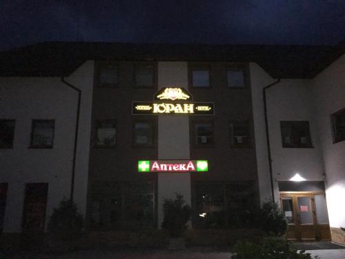 a building with a sign for a hotel at night at Гостевой дом Юран in Mizhhirʼʼya