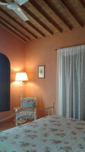 a bedroom with a bed and a chair and a lamp at Podere La Fausta in Serravalle Pistoiese