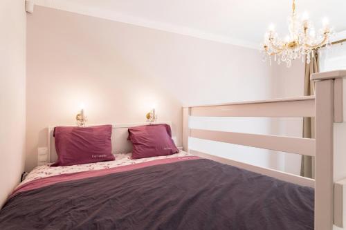 ブダペストにあるLuxury & Antique Charmのベッドルーム1室(紫色の枕とシャンデリア付きのベッド1台付)