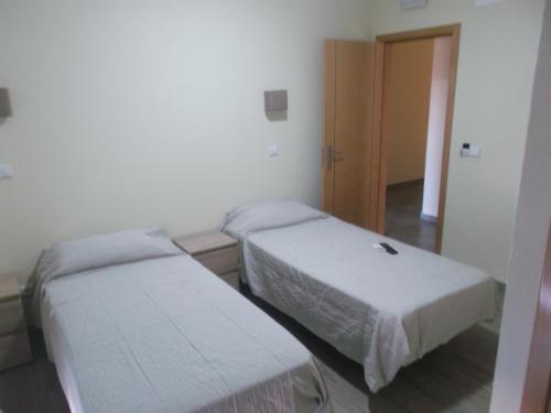 two beds in a small room with a door at Guest House Sabores da Beira in Castro Marim
