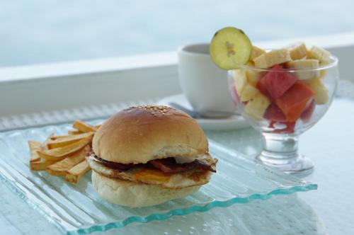 a sandwich and chips on a plate with a bowl of fruit at Aquaterrace Amed in Amed