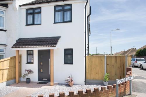a white house with a black door and a wooden fence at Northwood 2 in Broadstairs