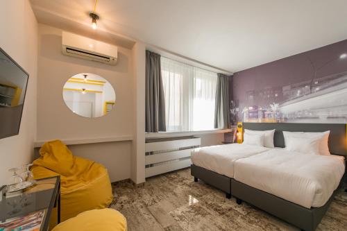 a hotel room with two beds and a yellow chair at Three Corners Hotel Anna in Budapest