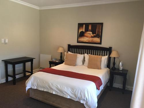 1 dormitorio con 1 cama grande y 2 mesas en Lavender Lodge, en Vryburg