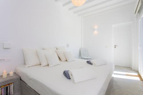 a white bedroom with a large white bed with white pillows at Elia Sea View Luxury Villa in Elia Beach