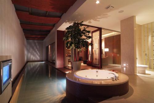 a bathroom with a tub and a tv in it at Lu Kang Villa Spa in Lugang