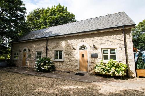 a small brick building with a door and flowers at Normanton Park Hotel, Sure Hotel Collection by Best Western in Oakham