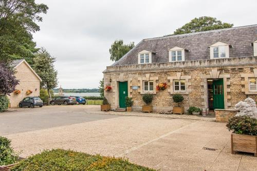 a stone house with green doors and a parking lot at Normanton Park Hotel, Sure Hotel Collection by Best Western in Oakham