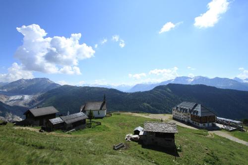 a group of buildings on a hill with mountains in the background at Hotel Belalp in Belalp