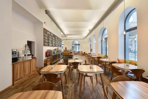 um restaurante com mesas e cadeiras de madeira e janelas em Hotel Mocca em Viena