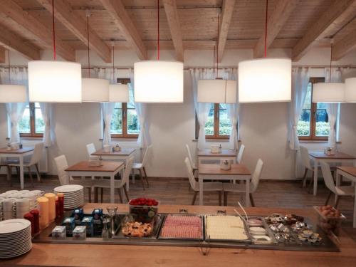 una sala da pranzo con tavoli, sedie e lampadari a braccio di Seehotel am Hallstättersee a Obertraun