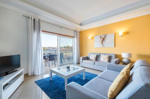 - un salon avec un canapé et une télévision dans l'établissement Lakeside Country Club - Apartamentos Turísticos, à Quinta do Lago