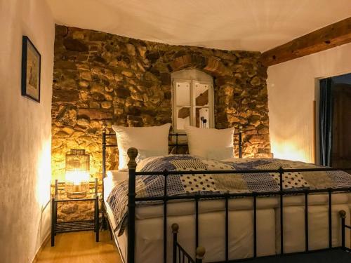 a bedroom with a bed in a stone wall at Hotel Zum Burggraf in Neuleiningen
