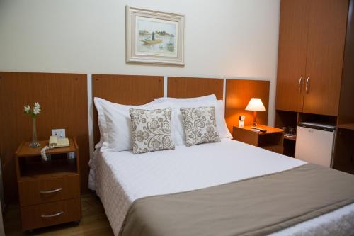a bedroom with a large bed with white sheets and pillows at Kafé Hotel in Guaratinguetá